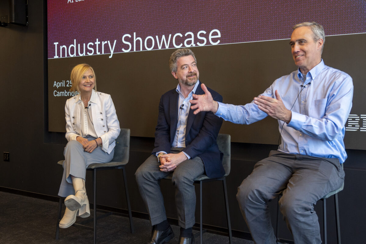From left: Aude Oliva, David Cox, and Dan Huttenlocher sit on tall chairs in front of the Lab's Industry Showcase logo on a screen